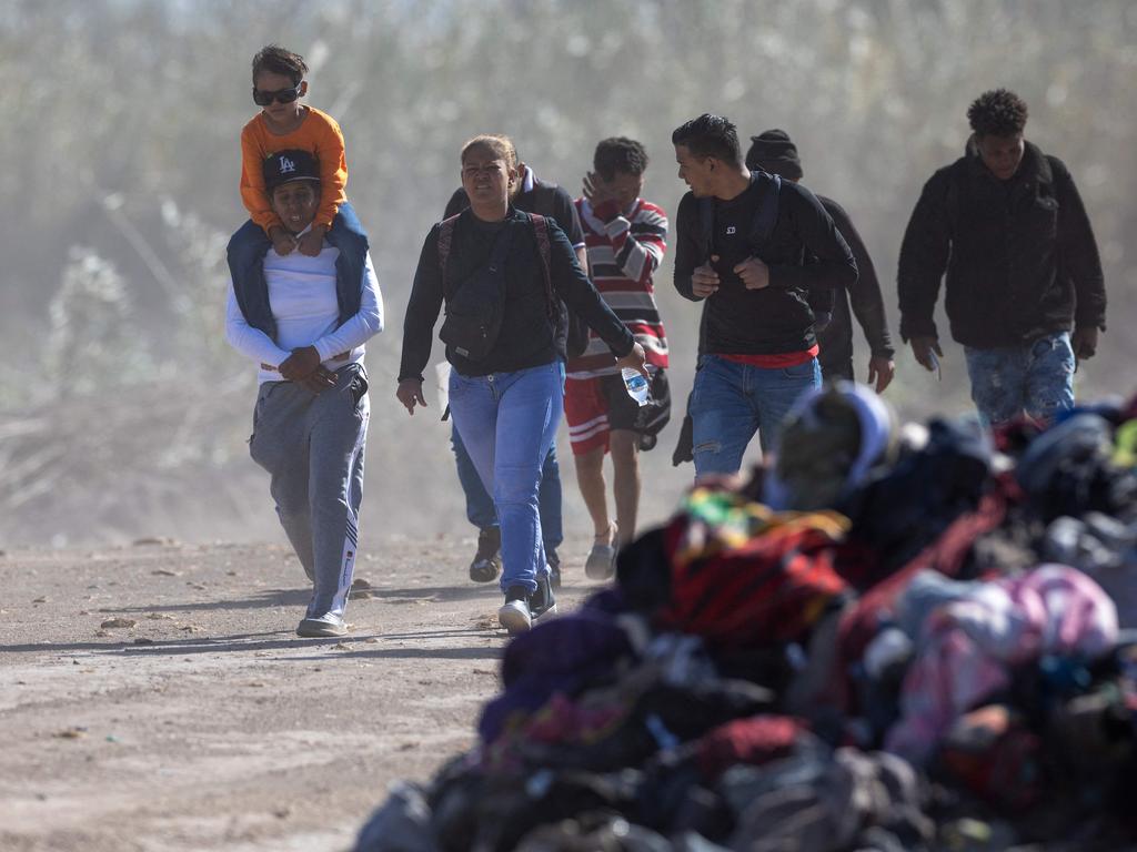 Immigrants from Venezuela walk past a pile of discarded migrant clothing after crossing the Rio Grande into the United States.