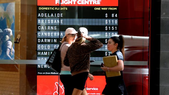 Pedestrians pass a Flight Centre in central Melbourne advertising cheap air travel.