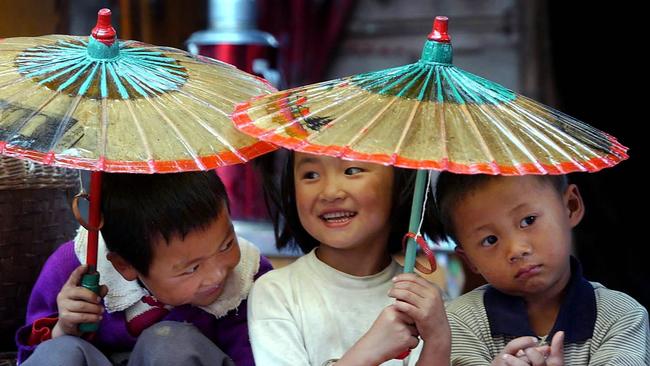 Local children sit tight together under traditional oilpaper umbrellas at Yunyang village in southwest Yunnan Province, China.