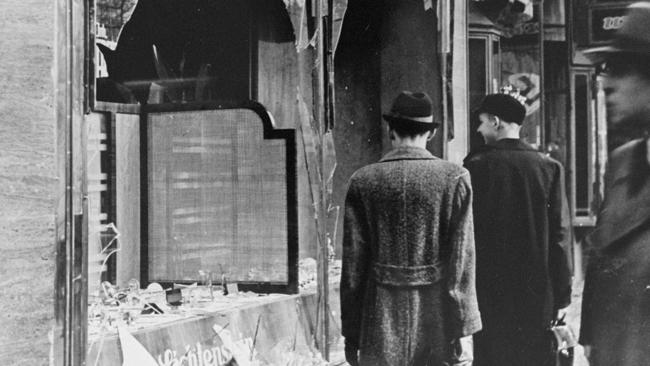 Germans pass by the broken shop-window of a Jewish-owned business destroyed during Kristallnacht, Berlin, 1938.