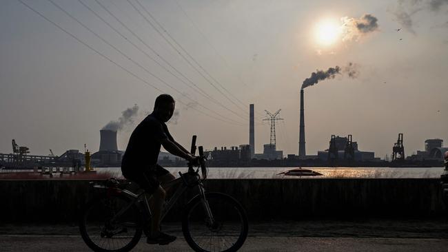 A man rides a promenade along the Huangpu river across from the Wujing Coal-Electricity Power Station in Shanghai. Picture: AFP