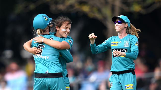 Amelia Kerr of the Heat (centre) hugs teammate Beth Mooney and joined by Kirby Short (right) as she celebrates taking the wicket of Suzie Bate. (AAP Image/Dan Peled)