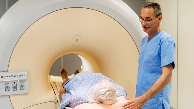 Male radiologist is talking to a patient who is about to receive a medical scan for prostate cancer.