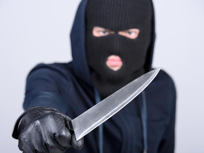 Masked man aims with knife. on gray background. Robbery, crime, knife generic