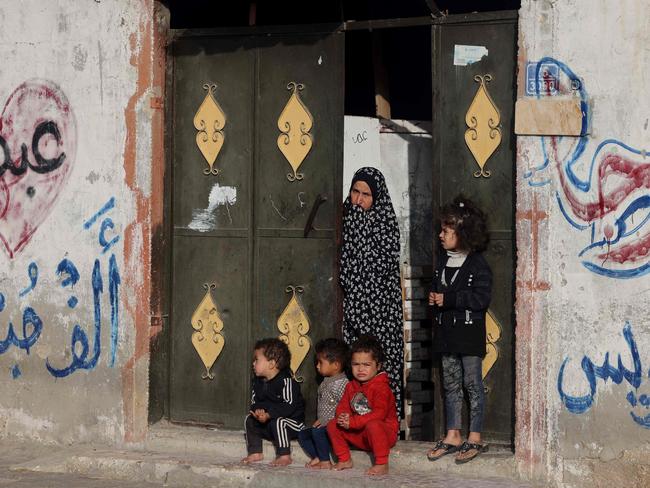 A Palestinian woman stands next to children at the gate of their home during the funeral of twin babies killed in an overnight Israeli air strike in Rafah. Picture: AFP