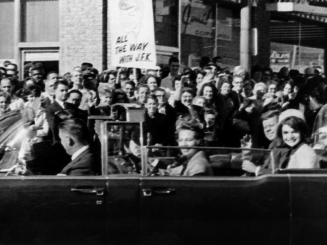 US President John F Kennedy with wife Jackie ride in the rear seat of a limousine car as the crowds cheer in Dallas just moments before he was shot dead by Lee Harvey Oswald.