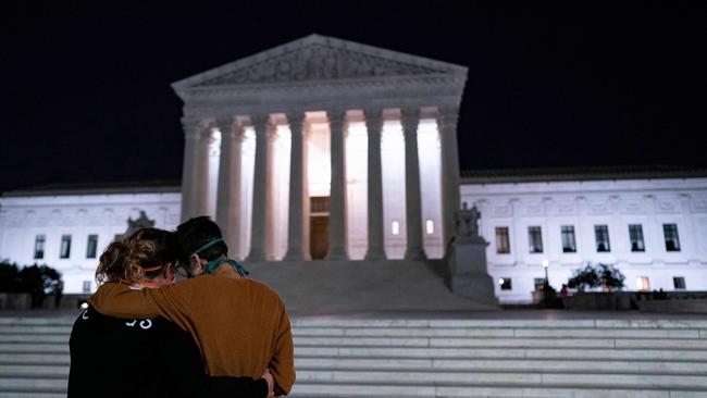 Two women embrace in front of the Supreme Court buidling paying their respects to Justice Ruth Bader Ginsburg.