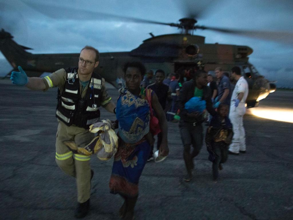 People rescued by helicopter get helped off the aircraft. Picture: Josh Estey/CARE