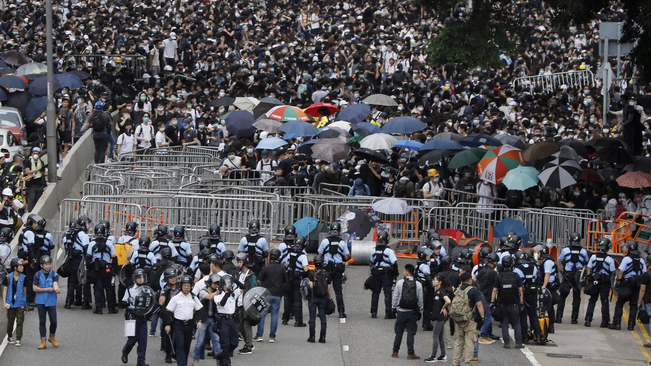 Policemen in anti-riot gear stand guard against the protesters on a closed-off road near the Legislative Council. Picture: Vincent Yu/AP