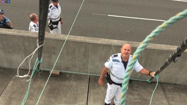 Police seen working out how to bring the suspended protester down- have since arrested the man.