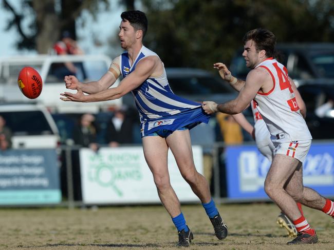 Langwarrin co-captain Nick Hammill gets a handball away as Karingal’s Nathan McDonald applies pressure. Picture: Chris Eastman