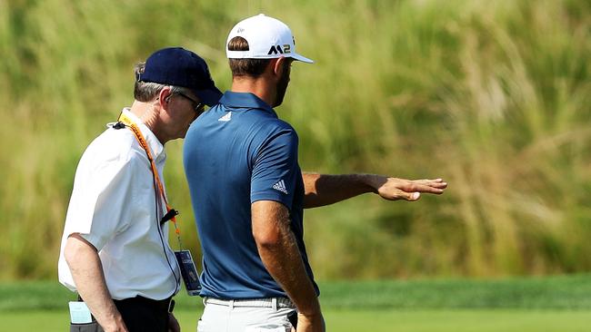 Dustin Johnson chats with a rules official on the fifth green at Oakmont Country Club.