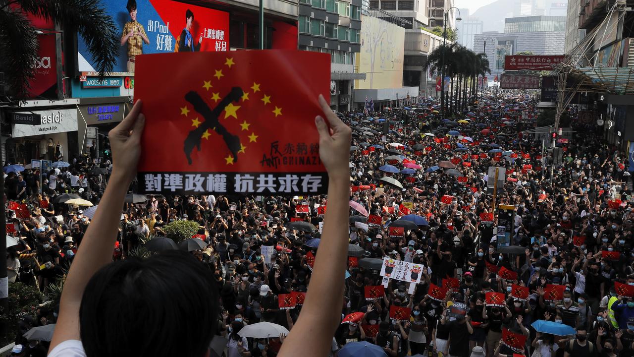 A protester holds up a placard reading "Aligning the regime, Anti Communist survival" as demonstrators march in Hong Kong on October 20, 2019. Hong Kong protesters again flooded streets on Sunday, ignoring a police ban on the rally and demanding the government meet their demands for accountability and political rights. Photo: Kin Cheung/AP