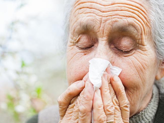 An elderly sick woman blows her nose outdoors. Picture: Generic