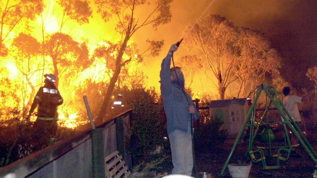 Firefighters battle flames as fire threatened homes around Powderworks Road at Ingleside, in 2001. Picture: John Grainger