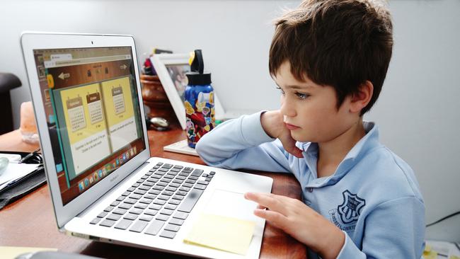 Phoenix Crawford does school work on a laptop while being home-schooled by his mum Donna Eddy in Sydney. Picture: Getty Images