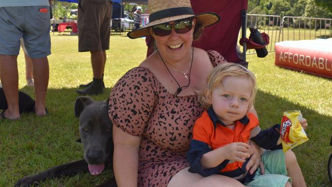 Kristy, Declan E and their dog Judge sitting in the grass by the jumping castle on Australia Day.