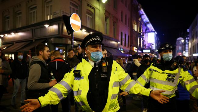 Police officers wearing protective face masks are seen moving people on as pubs close ahead of the lockdown in Soho, London. Picture: Henry Nicholls/Reuters