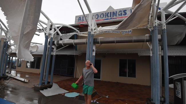 A local inspects damage to a boat terminal at Shute Harbour, Airlie Beach. Picture: AAP.