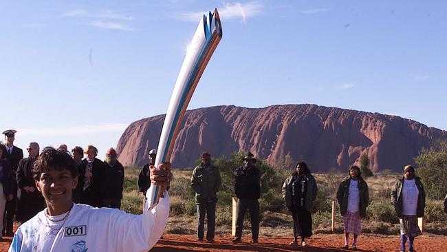 Athlete Nova Peris Kneebone and traditional Indigenous custodians owners with the Olympic torch at Uluru in June 2000 ahead of the Sydney Games.