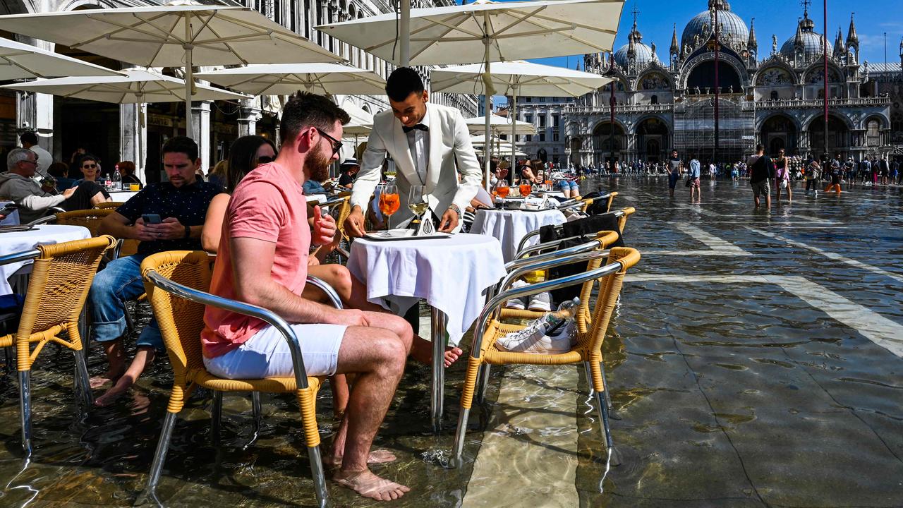 Tourists get their drinks served at a cafe's terrace on a flooded St. Mark's square in Venice on September 27, 202. Picture: Andrea Pattaro/AFP