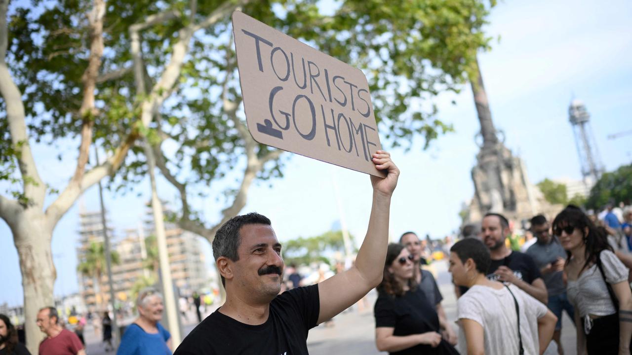 A man holds a sign saying ‘tourists go home’. Picture: Josep Lago / AFP