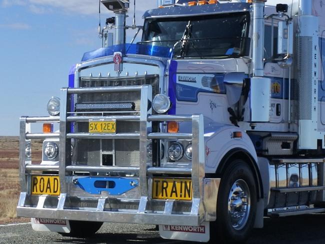 Coober Pedy, South Australia - May 20 2019: Three-trailer road train driving in central Australia Outback.Road train is a trucking vehicle used in remote areas of Australia,USA and Europe to move freight efficiently.