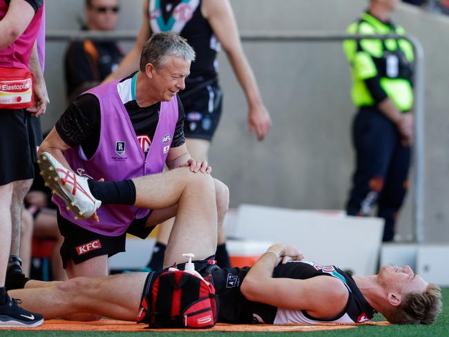 Todd Marshall of the Power is assessed by a club physio on the Gold Coast. Picture: Russell Freeman/AFL Photos via Getty Images.