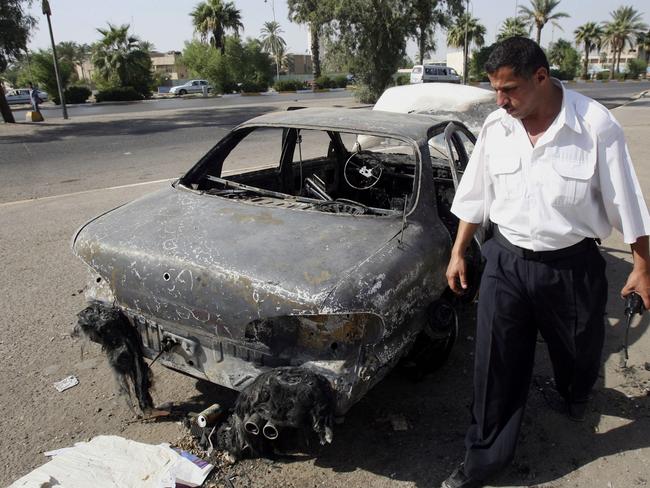 Devastation ... an Iraqi traffic policeman inspects a car destroyed by a Blackwater security detail in al-Nisoor Square in Baghdad, Iraq. Picture: AP