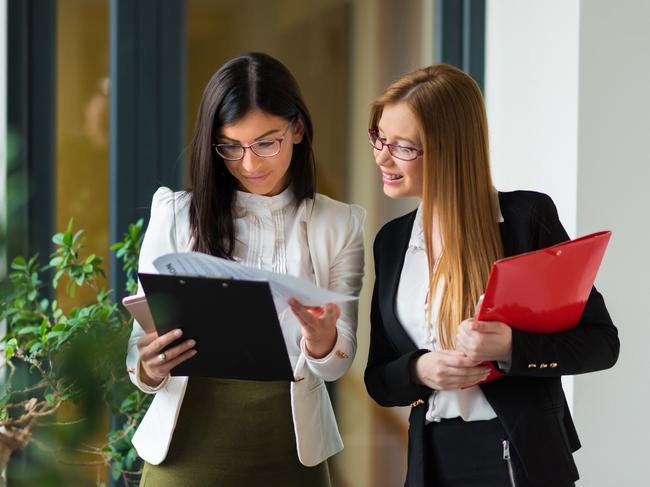 CAREERS: First time as a mentor, with a mentee. Picture: iStockTwo women in a office lobby discusing about work, looking at some papers and documents together, trying to find solutions