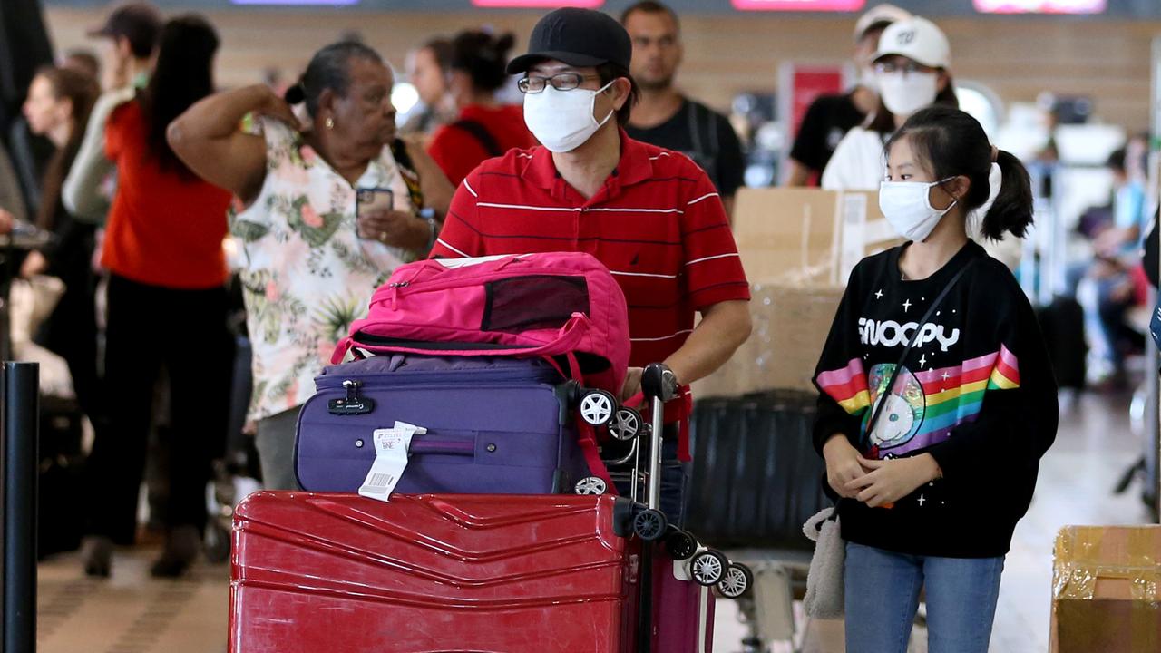 Travellers at Brisbane Airport wear masks after the outbreak of coronavirus. Picture: Steve Pohlner