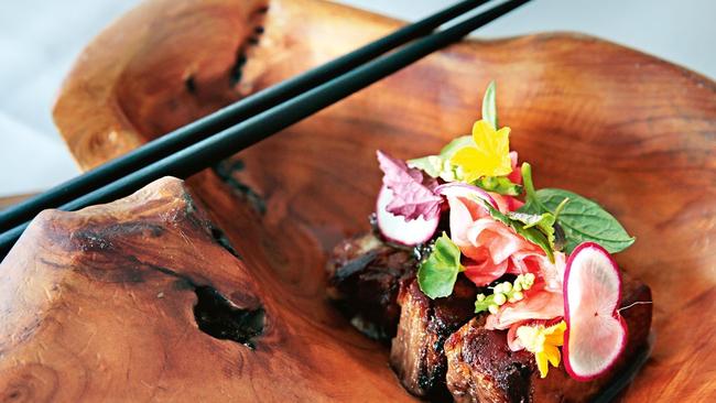 The soy and Okinawa black sugar braised lamb belly grilled over white charcoal with seri leaf pickled radish and aged black rice vinegar and shallot dressing. Picture:  Lachie Millard