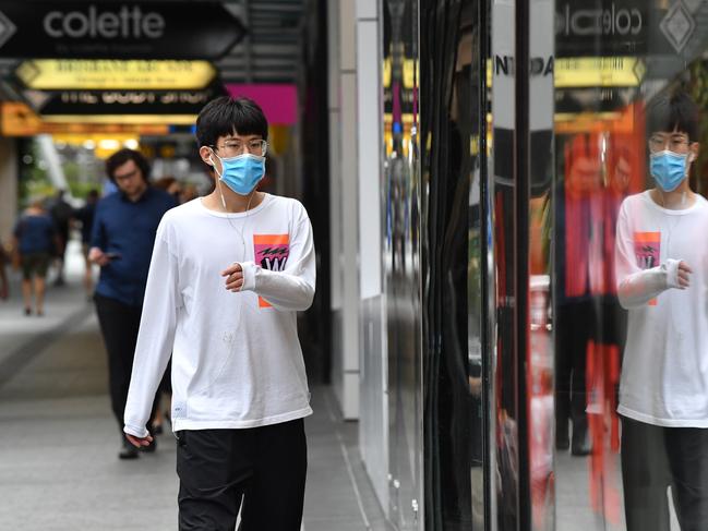 A man wearing a protective face mask is seen walking along the Queen Street Mall in Brisbane. Picture: AAP