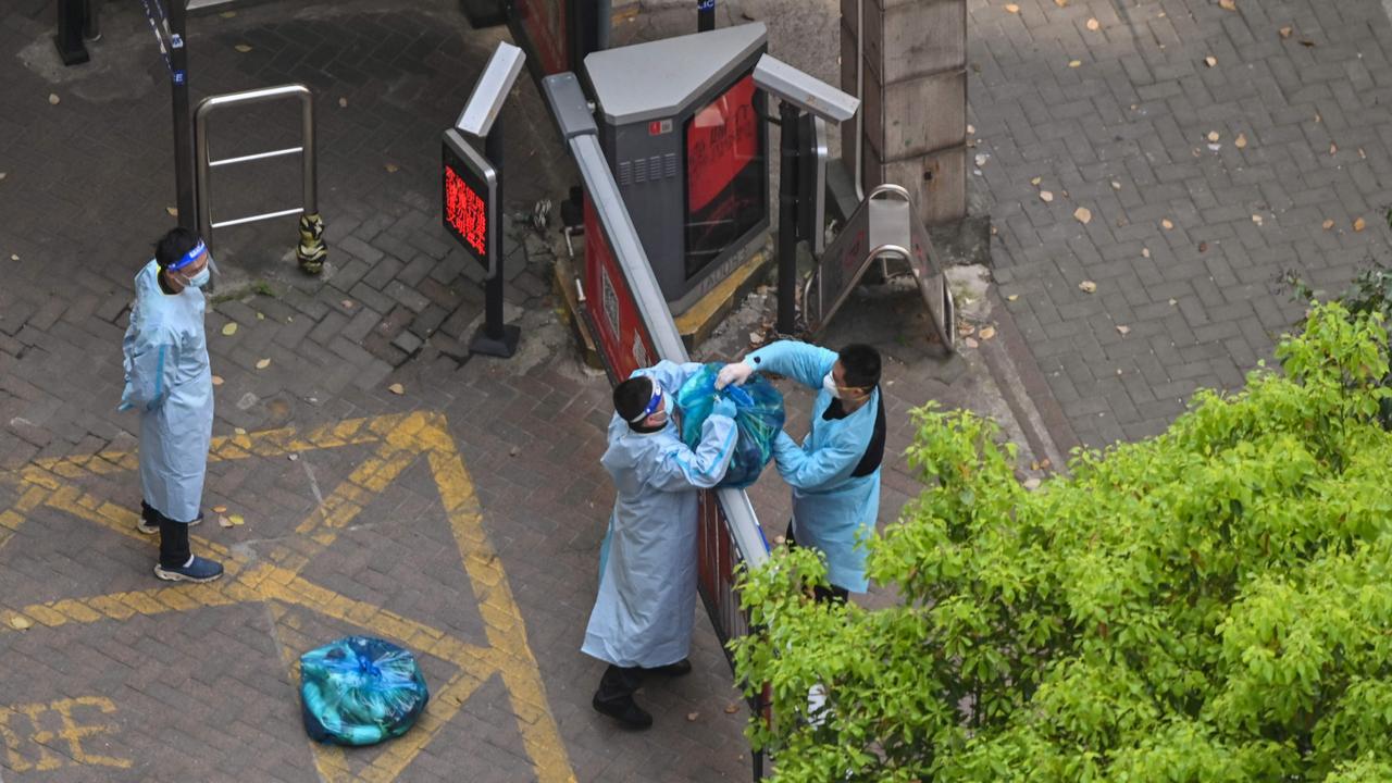 A guard receives goods from a delivery worker in a compound during a COVID-19 lockdown in Shanghai. Picture: AFP.