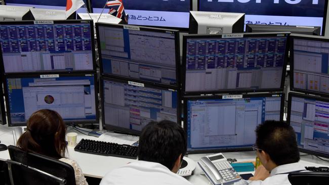Traders ckeck computer screens showing the Japanese yen rate against the British pound at a brokerage in Tokyo on October 7, 2016 after the pound suffered a 