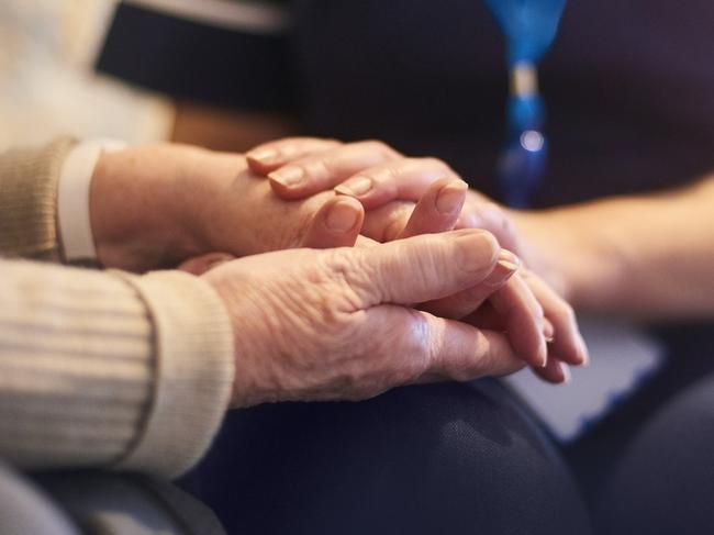 A female nurse consoles a senior patient at home, aged care generic