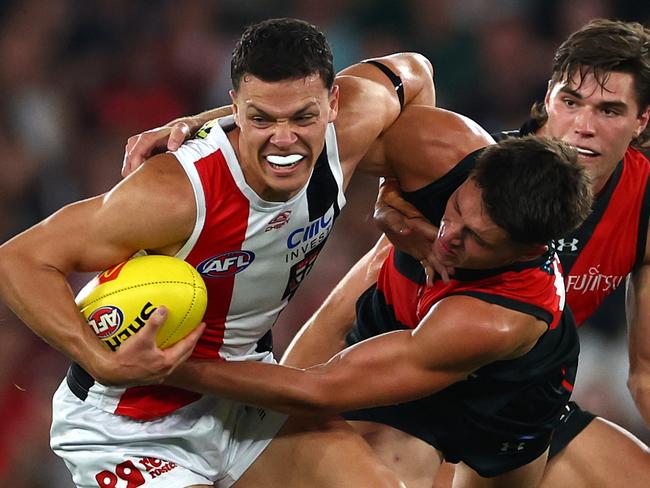 MELBOURNE, AUSTRALIA - MARCH 30: Marcus Windhager of the Saints is tackled by Archie Perkins of the Bombers during the round three AFL match between Essendon Bombers and St Kilda Saints at Marvel Stadium, on March 30, 2024, in Melbourne, Australia. (Photo by Quinn Rooney/Getty Images)