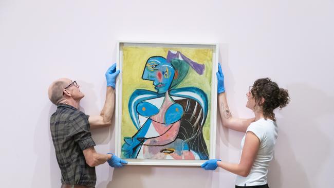 Exhibition installers with a Picasso painting at the gallery. Picture: Supplied