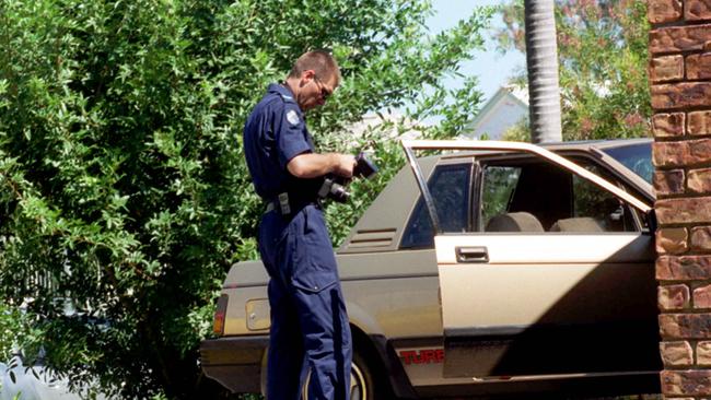 A police officer takes pictures of the vehicle that two children were found dead in at Sandstone Point. Picture: Andrew Maccoll