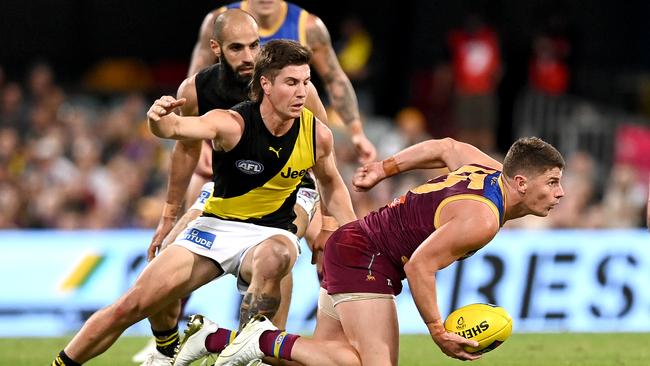 Dayne Zorko fires out a handpass in front of Richmond’s Liam Baker. Picture: Bradley Kanaris/Getty Images