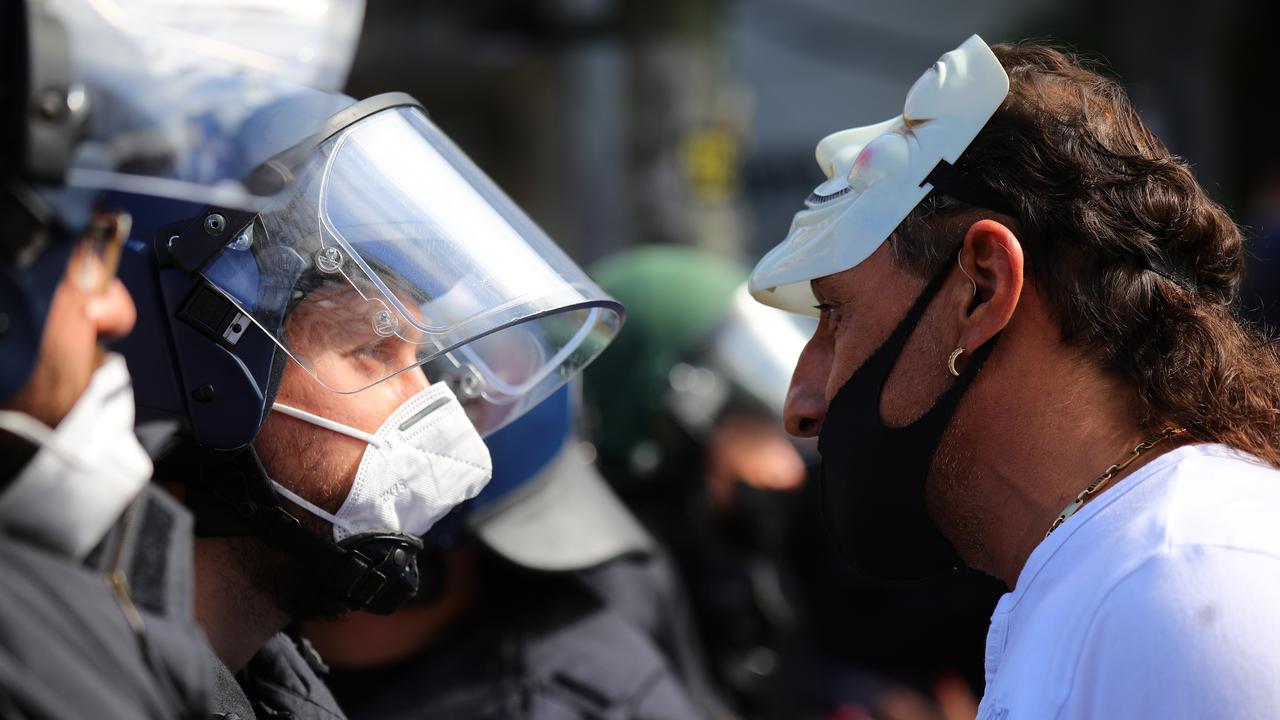 BERLIN, GERMANY - AUGUST 29: A man wearing a masquerade mask on his head speaks to a police officer at the Berlin rally.