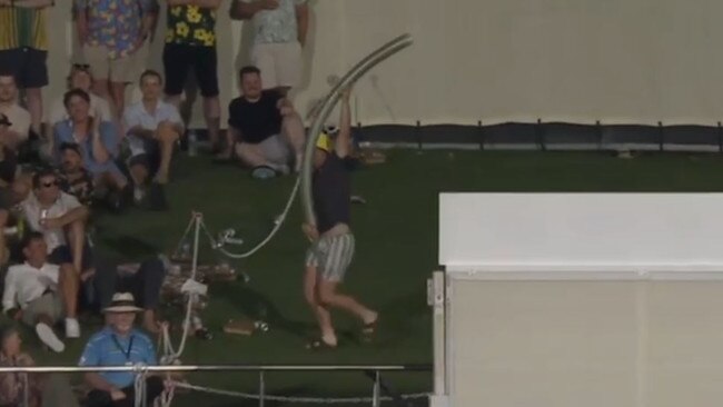 The fan and his giant beer snake safely exit the restricted area and play resumes. Picture: Fox Cricket