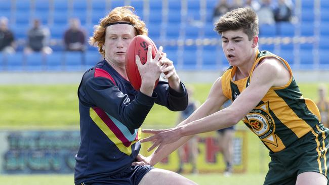 Guilford Young College’s Dom White, left, spins out of trouble during the SATIS grand final against St Patrick’s College. Picture: CHRIS KIDD