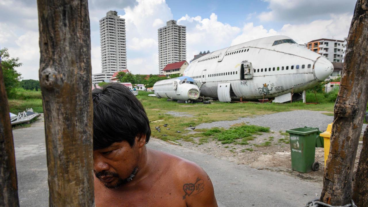 A man charges an entrance fee at a gate in front of abandoned aircraft in the suburbs of Bangkok. Picture: Mladen Antonov / AFP