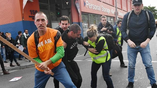 A left-wing protester brandishes a wooden club as fighting breaks out in the street. Picture: Jake Nowakowski