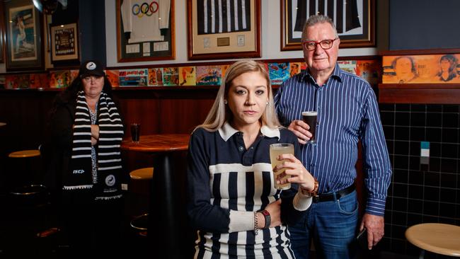 Shannon Burton wearing her dad Rod Burton’s guernsey, Port Adelaide Cheer Squad’s Jo Curyer and Alberton Hotel Director Peter Brien at the Alberton Hotel after hearing the news that Port can't wear the traditional prison bar jumper at the Showdown. Picture: Matt Turner.