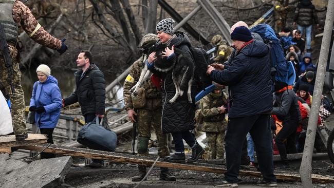 A woman carries a dog while crossing a destroyed bridge as Ukrainians evacuate the city of Irpin, northwest of Kyiv, during heavy shelling and bombing over the weekend. Picture: AFP