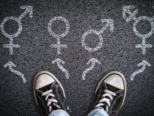 A person standing on asphalt road with gender symbols of male, female, bigender and transgender.  Concept of choice or gender confusion or dysphoria. Istock