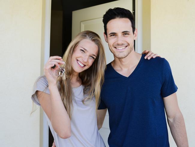 happy young couple man and woman handing over their new home keys in front of open house door