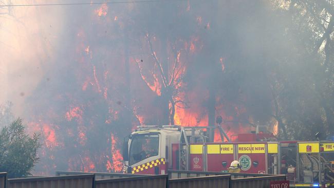 An out of control bushfire jumps Wine Country Drive and smashes head on into the village of North Rothbury, north of Cessnock. Picture by Peter Lorimer.